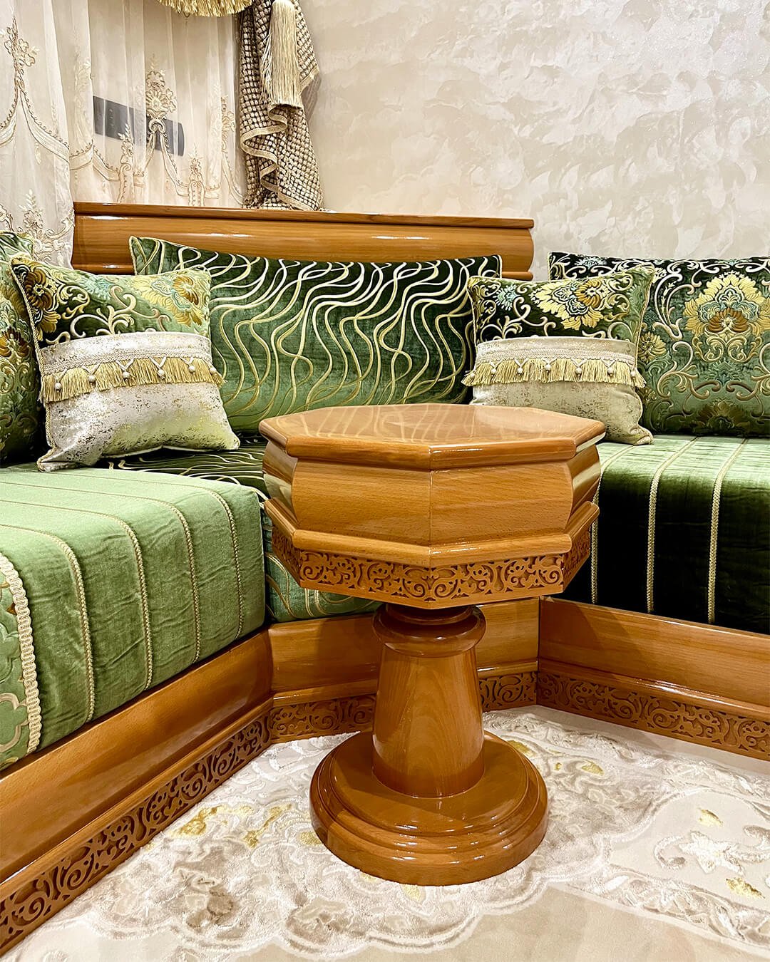 Petite table d’angle marocaine en bois sculpté, finition brillante, intégrée dans un salon marocain traditionnel vert et doré.