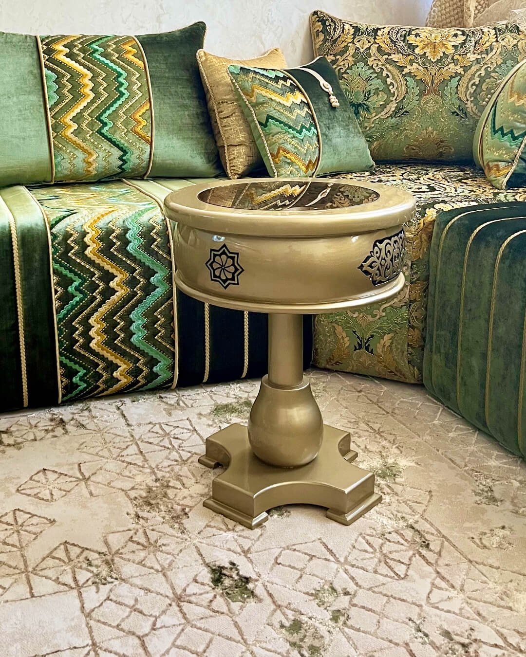 Petite table dorée de salon marocain en bois sculpté, posée dans un salon traditionnel vert et or.