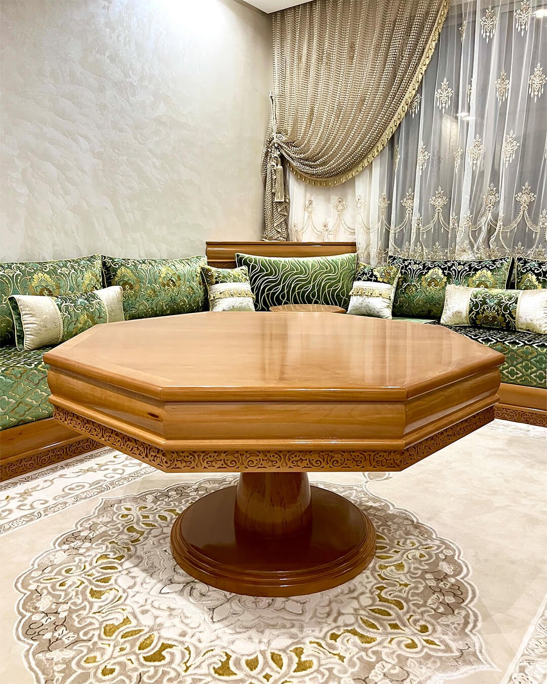 Table marocaine en bois massif, forme octogonale, avec gravures artisanales, au centre d’un salon marocain traditionnel.