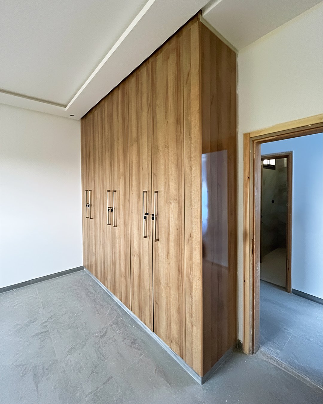 Placard d’angle sur mesure en MDF finition effet chêne avec poignées métalliques longues – installation murale moderne BOALUM